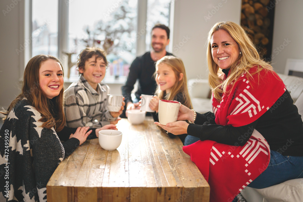 A family gathered around a wooden table with mugs of Sillycow hot chocolate on a bright winter afternoon